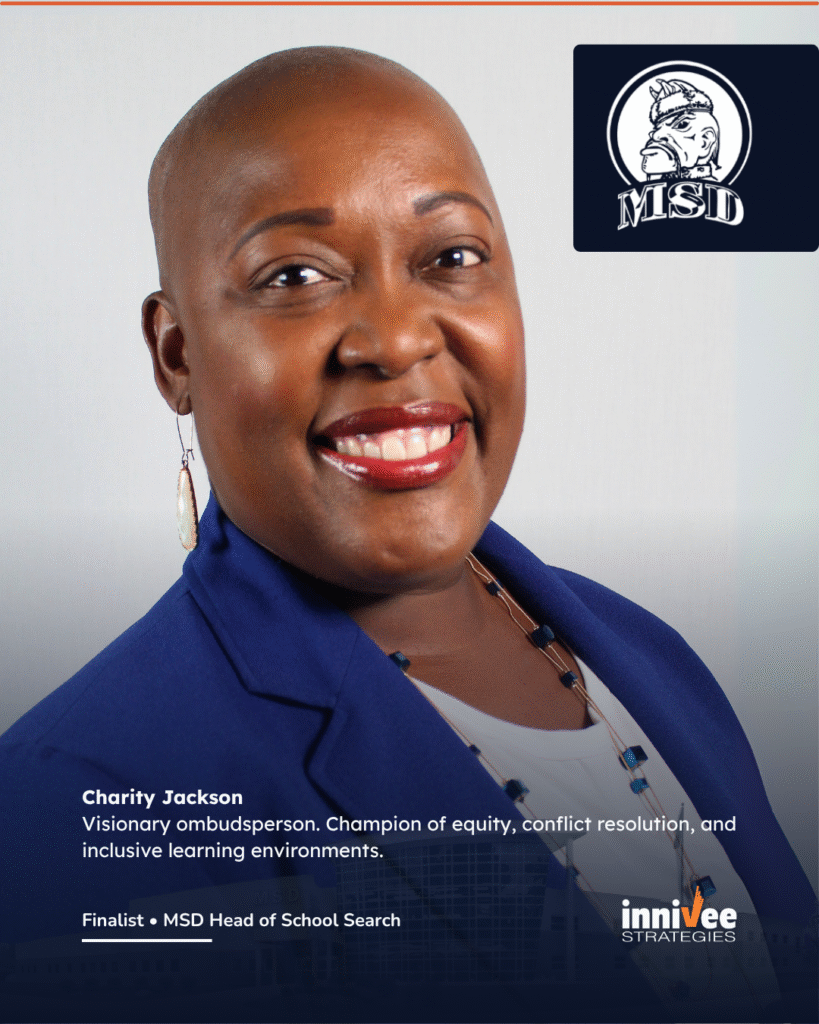 Finalists Announced for Michigan School for the Deaf 2 A professional headshot of Charity Jackson, a Black woman with a shaved head and bright smile, wearing a blue blazer and beaded necklace. She stands against a light gray background. The MSD logo is in the upper right. Below the photo, text reads:
“Charity Jackson
Visionary ombudsperson. Champion of equity, conflict resolution, and inclusive learning environments.
Finalist • MSD Head of School Search”
The Innivee Strategies logo appears at the bottom right over a subtle overlay of the MSD campus.