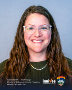 Smiling headshot of a person with long wavy brown hair, clear-framed glasses, and a small nose ring, wearing a dark green sweater and thin necklace against a light blue-gray background. Text includes their name and role; inniVee Strategies and Deaf TRAIL logos at bottom right.