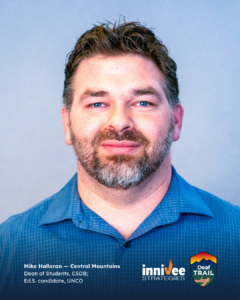 Headshot of a person with short curly hair and a trimmed beard, wearing a blue collared shirt against a light blue-gray background. Bottom text includes name, region, and roles; inniVee Strategies and Deaf TRAIL logos at bottom right.